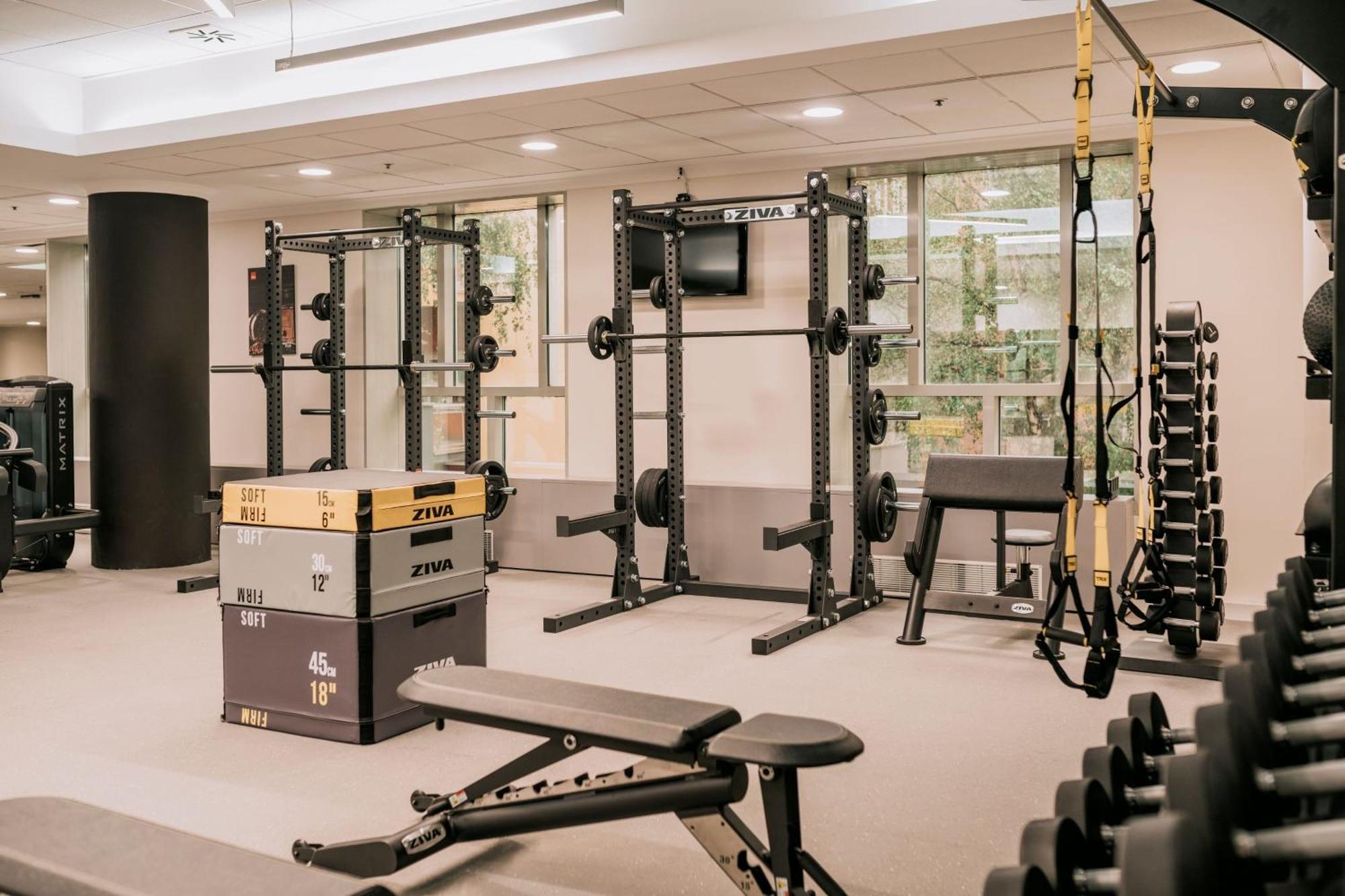 โรงแรมเชอราตัน ซาเกรบ ซาเกร็บ ภายนอก รูปภาพ The photo shows a well-equipped gym space. It features several weightlifting stations, including a squat rack and a multipurpose power rack, both equipped with weights. There are dumbbells on a rack along one side, and a flat bench is positioned for 